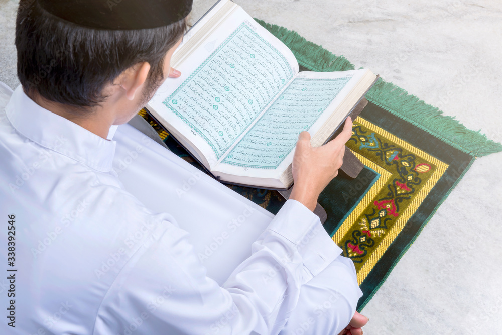 Asian Muslim man sitting and reading the Quran Asian Muslim man sitting and reading the Quran
