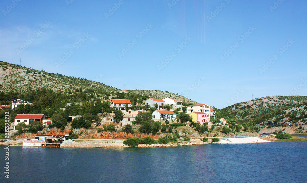 View of the shore of a lake, river, sea with beautiful small houses. Houses with red roofs, European places for tourism. Beautiful panoramic view of the birch from the boat.