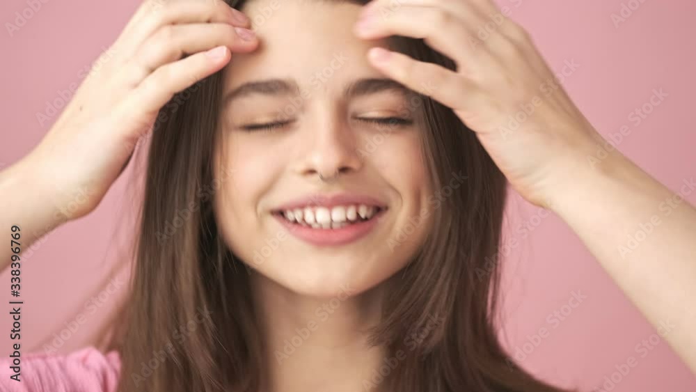 Close up view of happy pretty brunette woman in overalls having fun and showing peace gestures over pink background Close up view of happy pretty brunette woman in overalls having fun and showing peace gestures over pink background