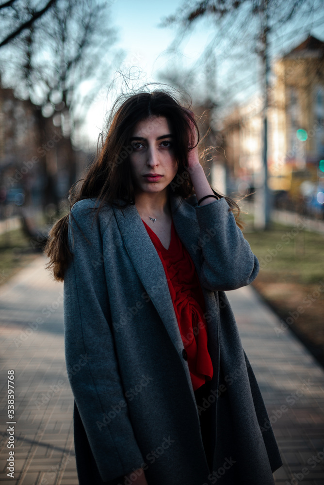 Girl in a red blouse and a gray cardigan on a blurry city background in early spring Girl in a red blouse and a gray cardigan on a blurry city background in early spring