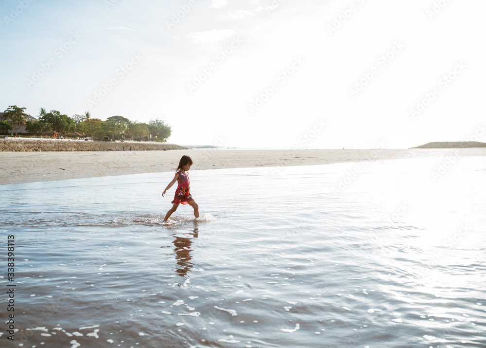 Little girl running on the beach while playing water on a beautiful beach Little girl running on the beach while playing water on a beautiful beach