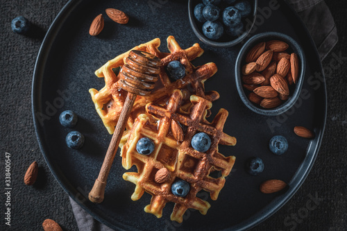 Top view of homemade waffles with blueberries, honey and almont