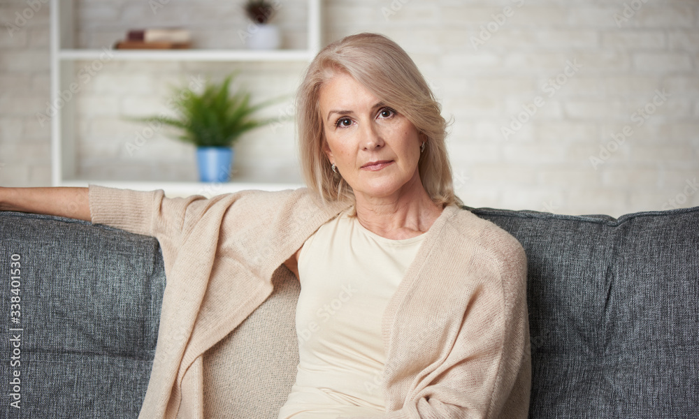 beautiful older blonde woman is sitting on a sofa