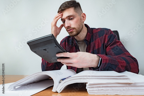 A man with a calculator against the background of many financial documents. Large amount of financial information. Checking the correctness of accounting. The company's budget. Financial calculation.