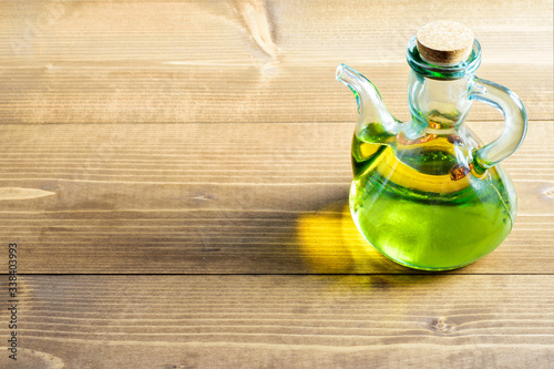 Olive oil in the glass bottle on the wooden table in sunlights. Healthy cooking and healthy eating.
