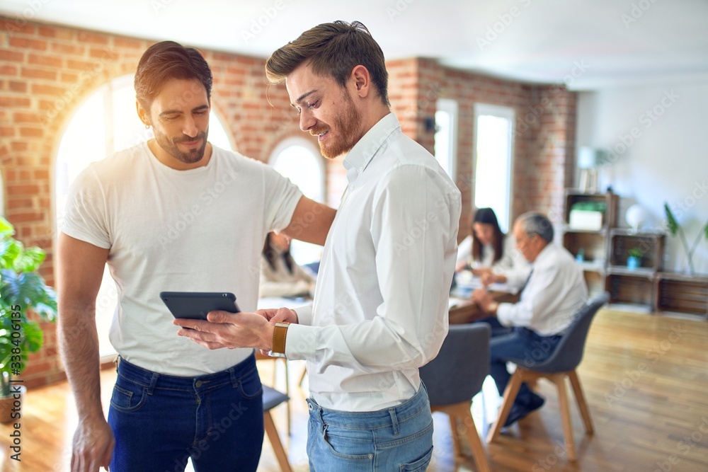 Business workers smiling happy. Standing with smile on face working together using tablet at the office