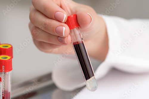 Doctor takes blood sample tube from tray on the table.