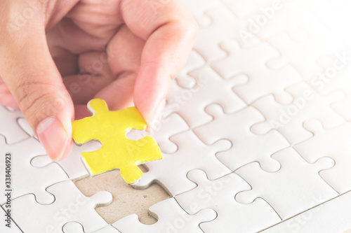 Pure white jigsaw puzzle with hand hold yellow one.