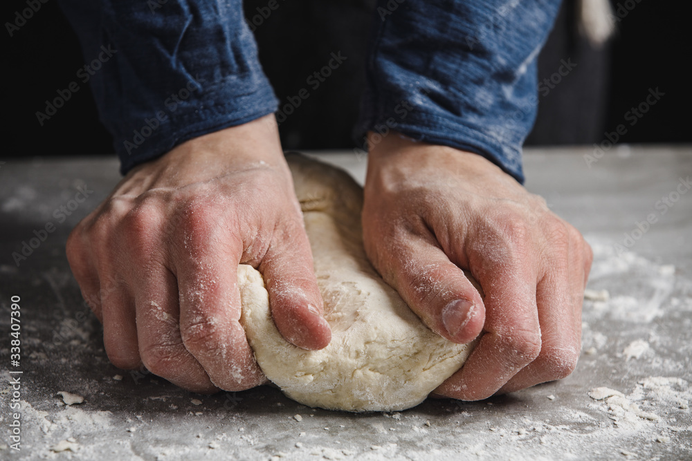 Thin male hands knead the dough for bread, pasta or pizza, close up.  Closeup hand of chef baker kneading a dough
