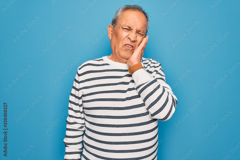 Senior handsome grey-haired man wearing striped sweater over isolated blue background thinking looking tired and bored with depression problems with crossed arms.
