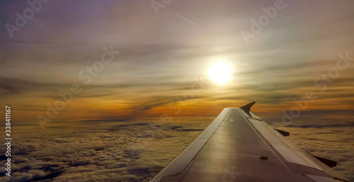 Photo of airplane wing in flight at sunset