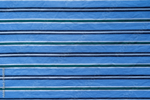 cloth pattern made of thin black, white and green stripes on blue background