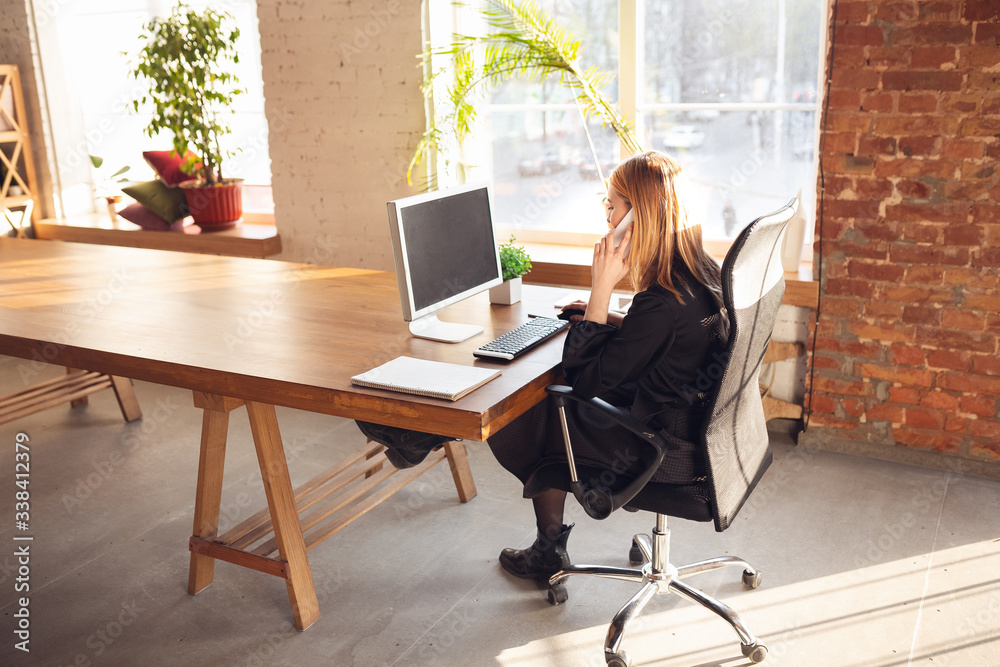 Talking on phone. Caucasian young woman in business attire working in office. Young businesswoman, manager doing tasks with smartphone, laptop, tablet has online conference. Finance, job. Talking on phone. Caucasian young woman in business attire working in office. Young businesswoman, manager doing tasks with smartphone, laptop, tablet has online conference. Finance, job.