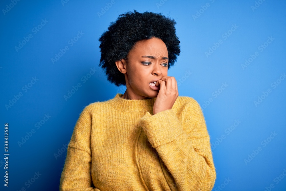 Young beautiful African American afro woman with curly hair wearing yellow casual sweater looking stressed and nervous with hands on mouth biting nails. Anxiety problem. Young beautiful African American afro woman with curly hair wearing yellow casual sweater looking stressed and nervous with hands on mouth biting nails. Anxiety problem.