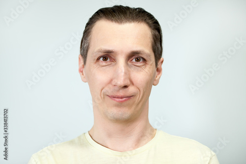 Portrait of a smiling and calm man, grey background, emotions series