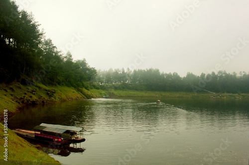 photo of a foggy freshwater lake located in the mountains with a rock hill as one of the boundaries