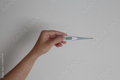 A hand holding a fever monitor, clipping path.