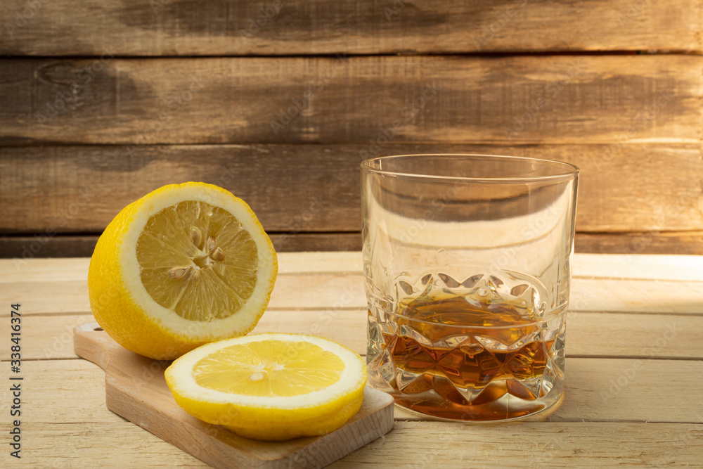 Cognac with lemon on a wooden background Cognac with lemon on a wooden background