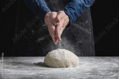 Thin male hands knead the dough for bread, pasta or pizza, close up. Closeup hand of chef baker kneading a dough. Male chef clapping hands with flour in kitchen 