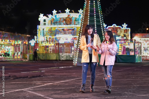 Photography Happy young eating candy sweets and looking smartphone at amusement park