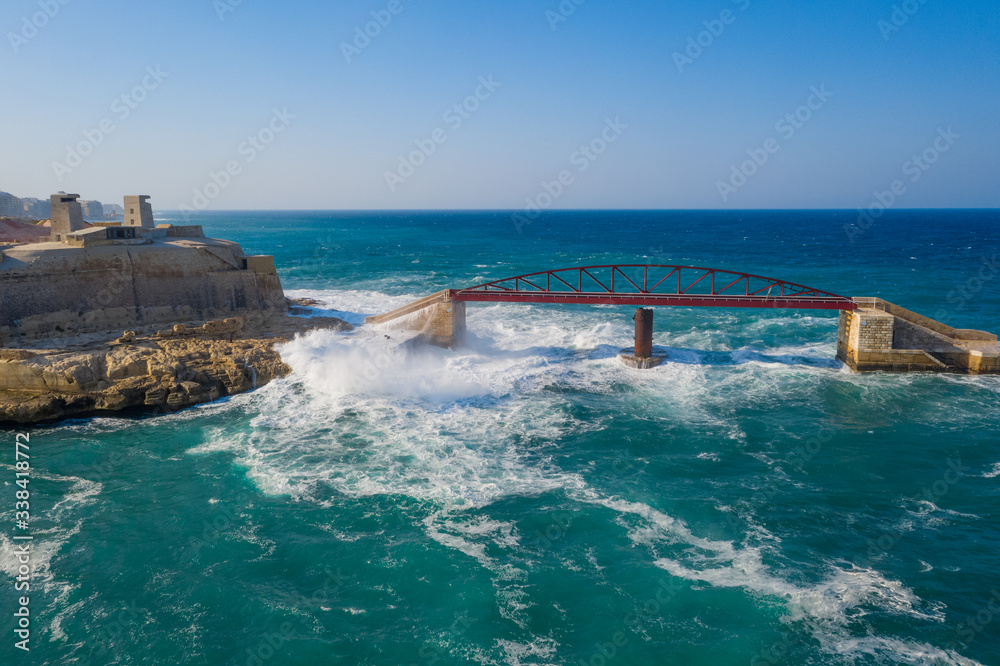 Aerial view of big waves on the red Breakwater Bridge during stormy weather. Valletta city, Malta island Aerial view of big waves on the red Breakwater Bridge during stormy weather. Valletta city, Malta island