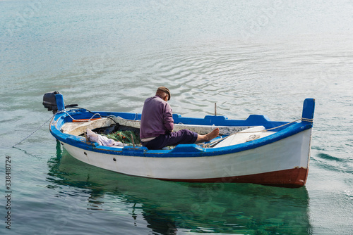 Fototapeta Naklejka Na Ścianę i Meble -  Fisherman repairs his fishing net in a boat in Cefalù; Sicily; Italy