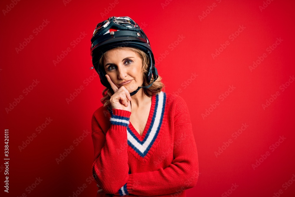 Obraz premium Middle age beautiful blonde motorcyclist woman wearing moto helmet over red background thinking looking tired and bored with depression problems with crossed arms.