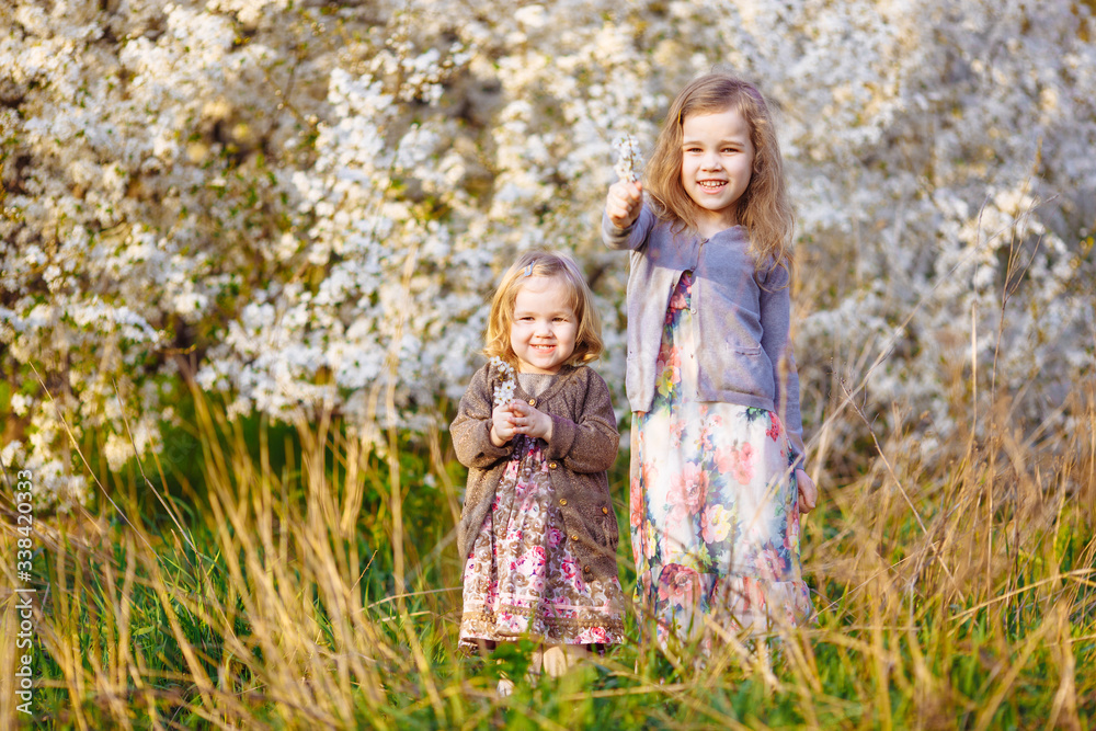 two little girls in blooming bushes with twigs two little girls in blooming bushes with twigs