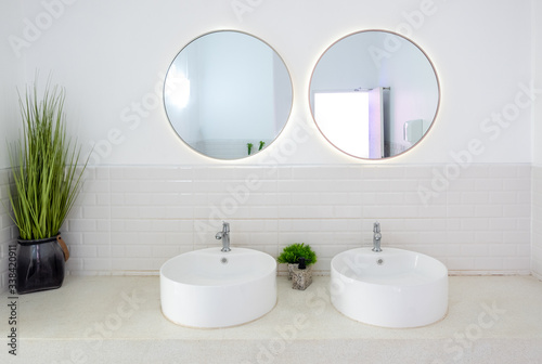 Modern public bathroom with white basin and circle mirror.