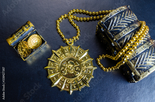 pirate medal, chest with gold coins on a black background
