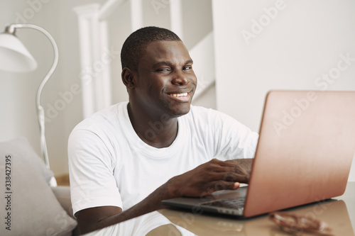 man of african appearance at home in front of a laptop