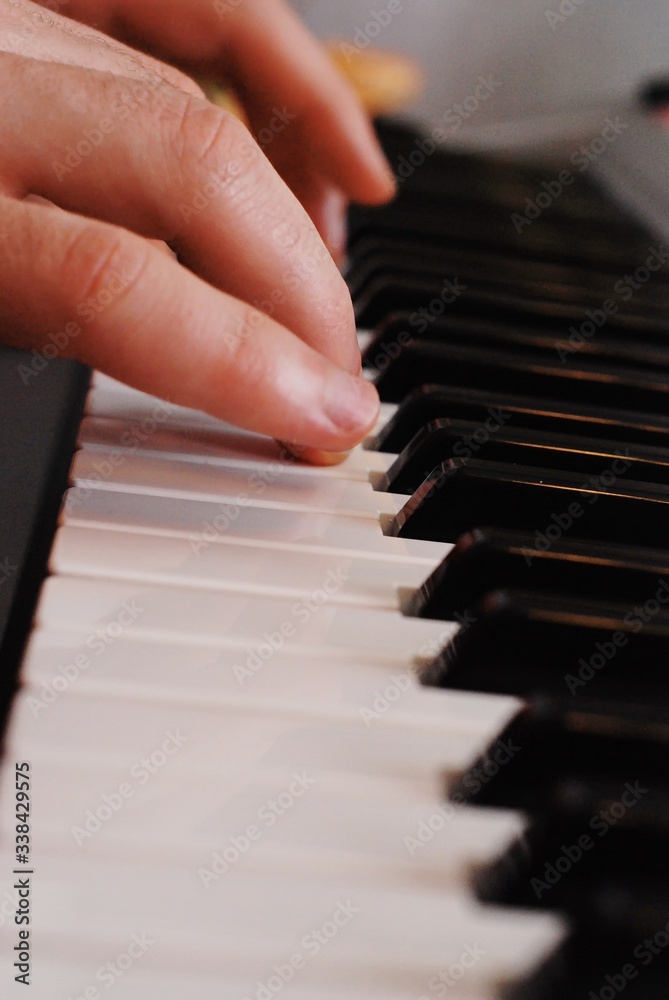 Obraz premium The musician plays the piano. The male fingers on the keys of the piano.