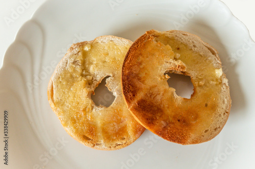 Vászonkép Toasted buttered bagel on a white plate