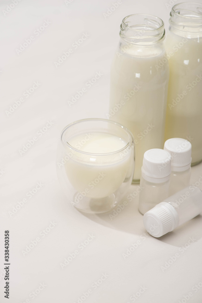 High angle view of bottles and glass of homemade yogurt near containers with starter cultures on white High angle view of bottles and glass of homemade yogurt near containers with starter cultures on white