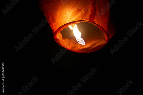 A red coloured sky lantern with the flames showing clearly lifiting off