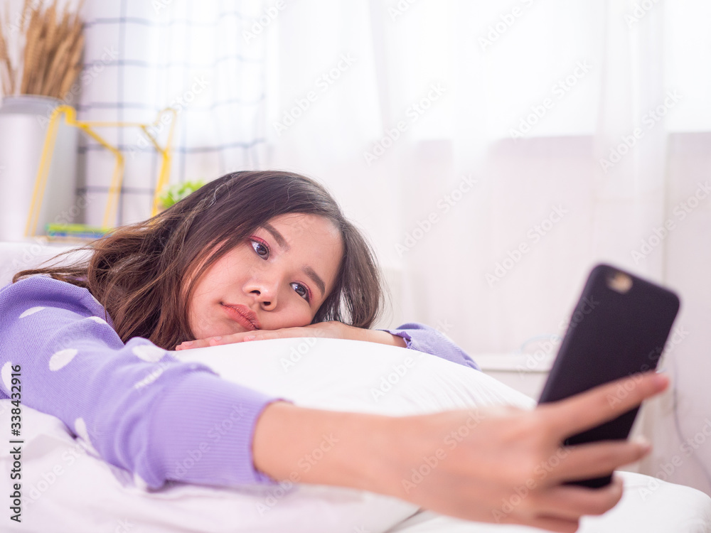 Asian women use mobile phones to watch Korean series and play games in bed. Feeling bored of the same behavior that must be at home to reduce the spread of the virus covid-19. Asian women use mobile phones to watch Korean series and play games in bed. Feeling bored of the same behavior that must be at home to reduce the spread of the virus covid-19.