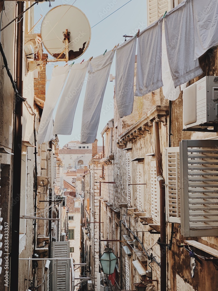 Narrow street of Dubrovnik, Croatia, Europe 2019. Travel concept. Old buildings with clotheslines across the street with white linen. Narrow street of Dubrovnik, Croatia, Europe 2019. Travel concept. Old buildings with clotheslines across the street with white linen.