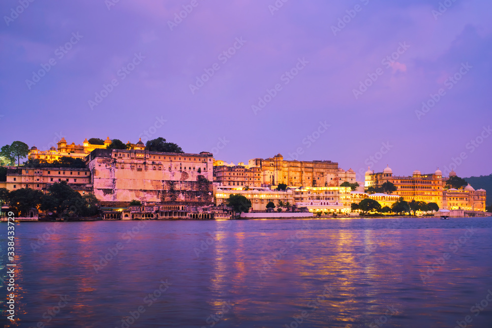 View of famous romantic luxury Rajasthan indian tourist landmark - Udaipur City Palace in the evening twilight with dramatic sky - panoramic view. Udaipur, India