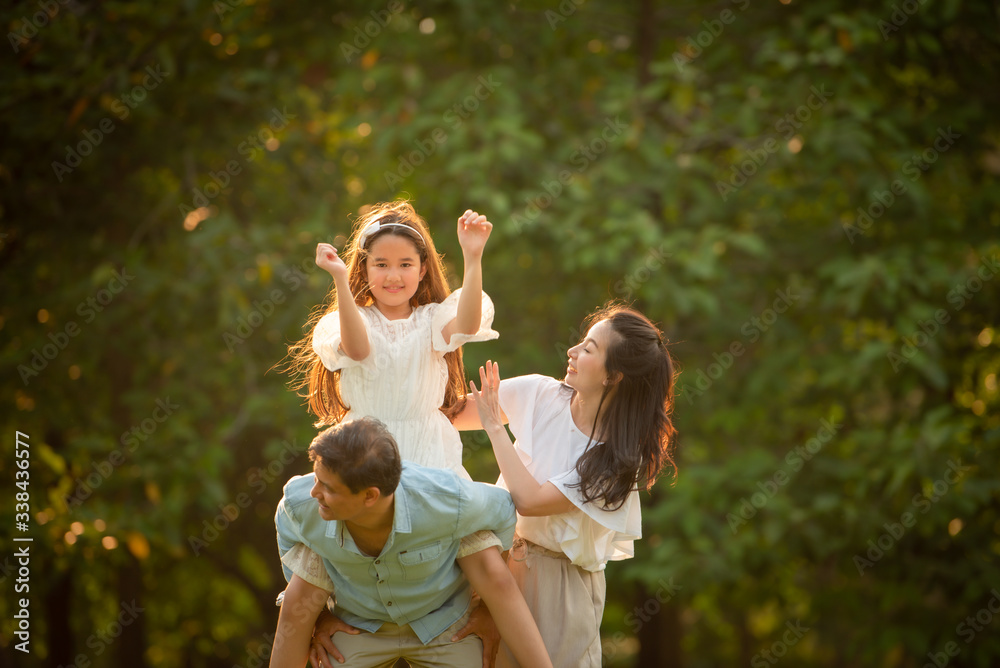 Happy family playing on the grass in the park at sunset. The concept of a happy family.