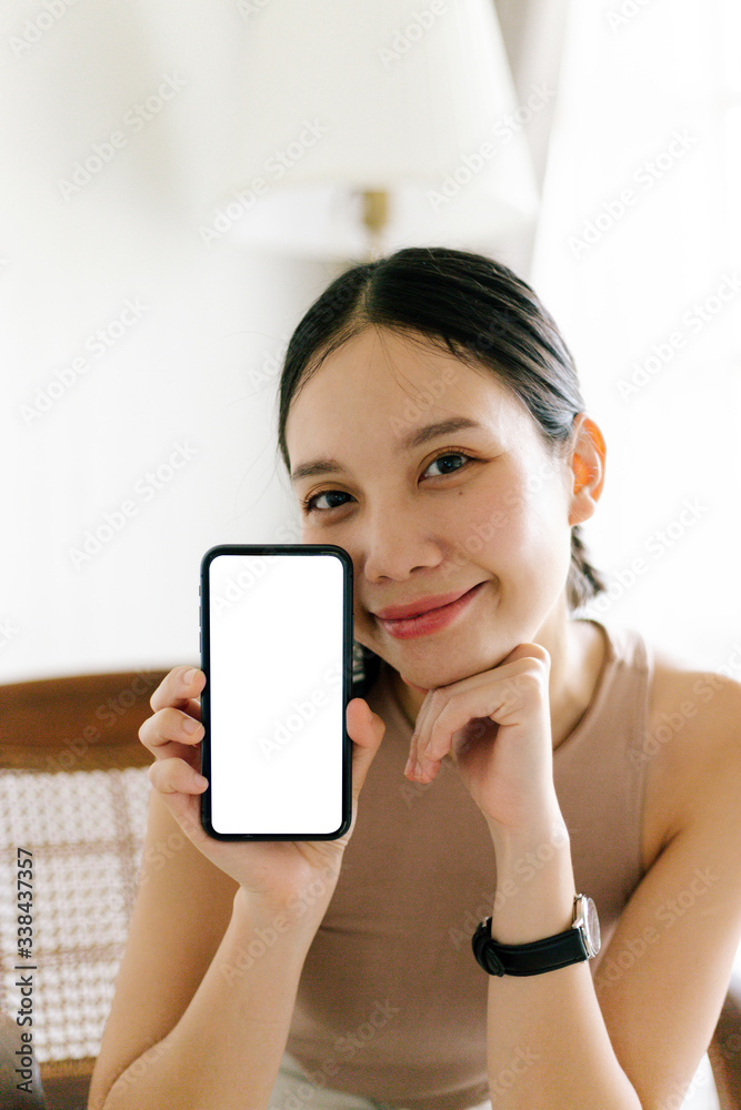 Asian cute woman is showing white blank smartphone screen on home studio background Asian cute woman is showing white blank smartphone screen on home studio background