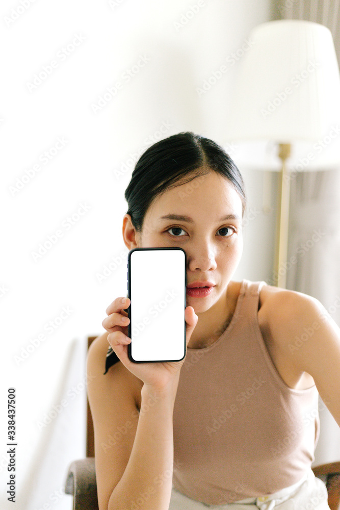 Asian cute woman is showing white blank smartphone screen on home studio background Asian cute woman is showing white blank smartphone screen on home studio background