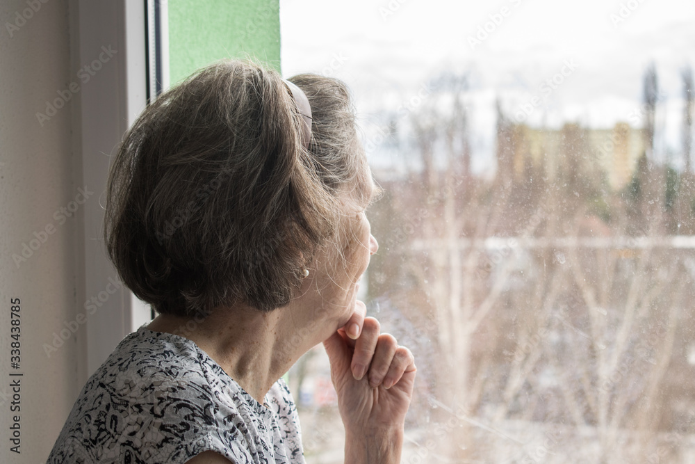  sad lonely old woman look next to  window allone depressed abandoned coronavirus stay home  - obrazy, fototapety, plakaty 