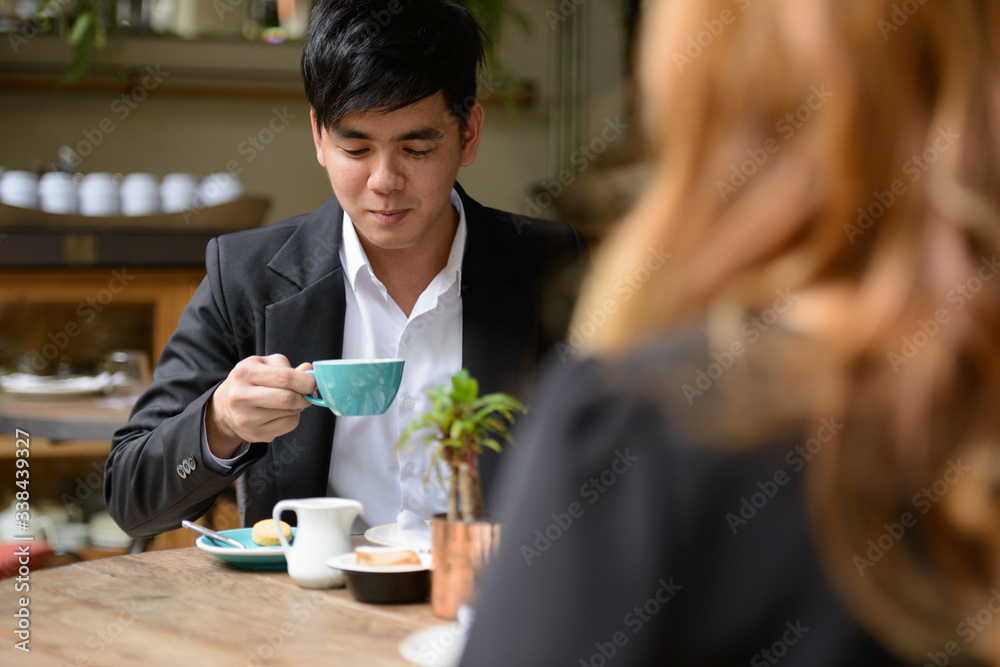 Young Asian business couple drinking coffee together at the coffee shop Young Asian business couple drinking coffee together at the coffee shop