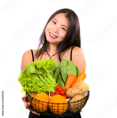 young happy and beautiful Asian Chinese woman holding basket full of fresh vegetables and fruits smiling cheerful in healthy organic and natural nutrition