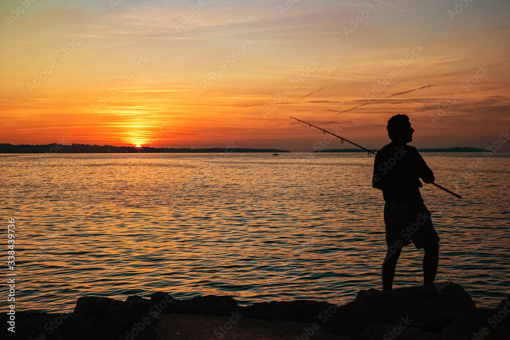 Fisherman silhouette at sunset in Fažana, Croatia