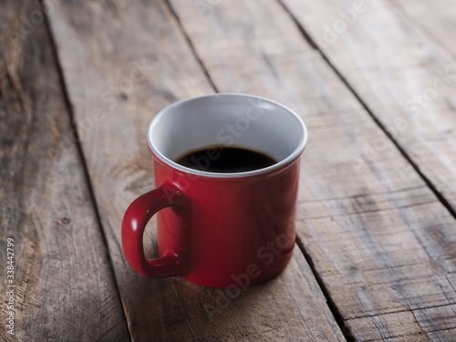 red mug of black coffee isolated on a wooden table