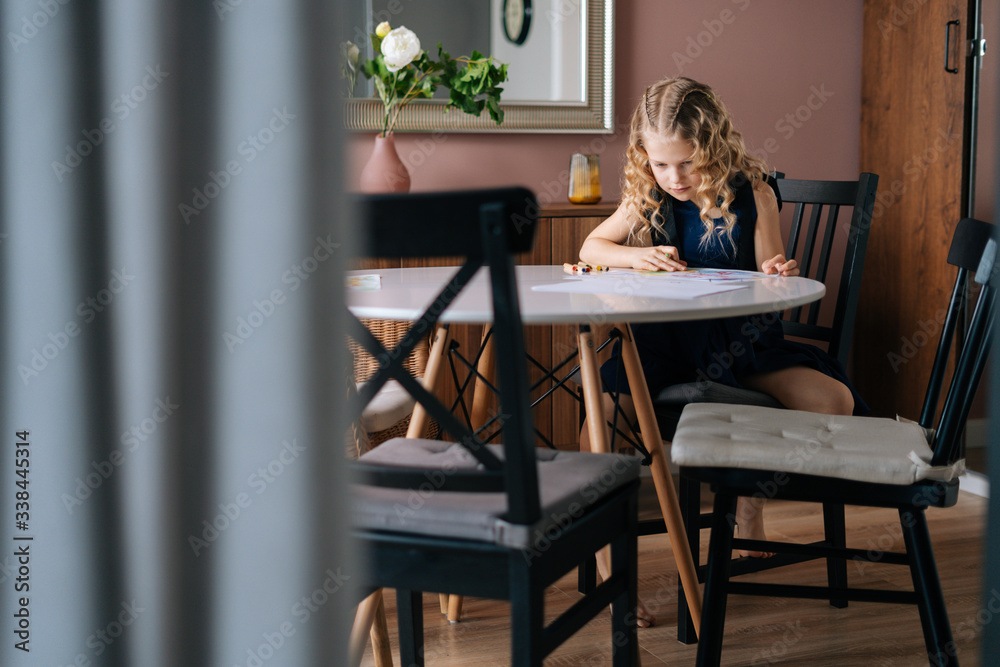 Creative kid girl doing homework at the table in cozy children's room. Concept of child creative activity. Creative kid girl doing homework at the table in cozy children's room. Concept of child creative activity.