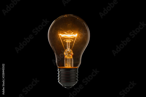 Old, dirty light bulb close up on black background photo