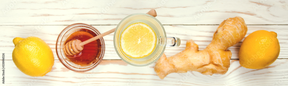 Drink hot tea with ginger-lemon and honey on white wooden background, prevention of colds. Selective focus Drink hot tea with ginger-lemon and honey on white wooden background, prevention of colds. Selective focus