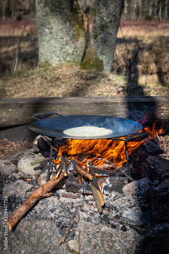 Open Fire cooking. Pancekes on a cast iron pan. Outside, nature, tracking, bushcraft.